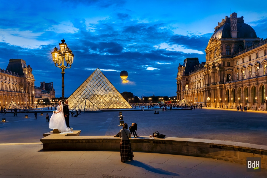 La cour Napoléon du Louvre, la Pyramide et la vasque olympique Paris 2024. Elle s'élève au dessus du jardin des Tuileries à 30 mètres. L'anneau contient la flamme, faite d'eau et de lumière 100% électrique, créée par le designer Mathieu Lehanneur